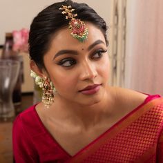 a woman in a red sari with earrings on her head