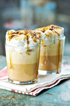 two glasses filled with dessert sitting on top of a table