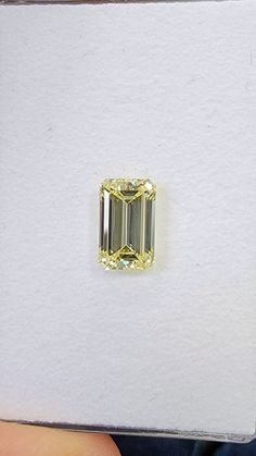 a yellow diamond is being held by someone