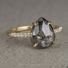 a large black and white diamond ring sitting on top of a gray surface with diamonds around it