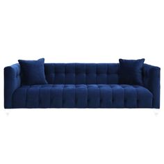 a blue velvet sofa with two pillows on it and one pillow in the shape of a rectangle