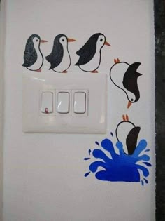 a white light switch with penguins painted on it