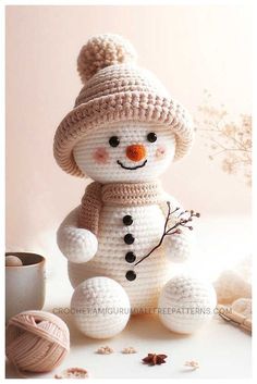 a crocheted snowman sitting on top of a table next to balls of yarn