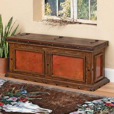 a large wooden trunk sitting on top of a rug in front of a potted plant