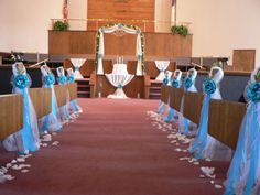 rows of pews decorated with blue sashes and flowers in front of the alter