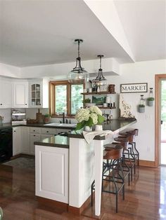 a kitchen with an island and bar stools in the center, surrounded by wood flooring