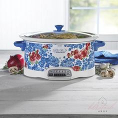 a blue and white crock pot sitting on top of a table next to an apple