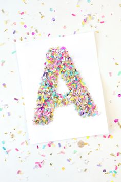 a letter made out of sprinkles sitting on top of a piece of paper