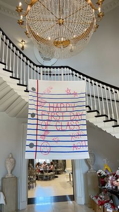 a sign hanging from the ceiling in front of a stair case and chandelier