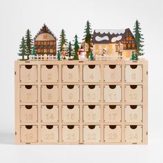 a wooden calendar with houses and trees on the top, in front of white background