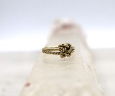 a gold ring sitting on top of a clear piece of glass with a knot in the middle