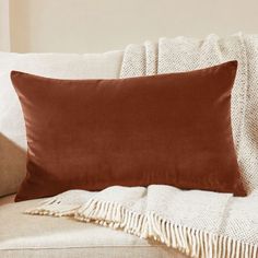 a brown pillow sitting on top of a couch next to a white blanket and pillows