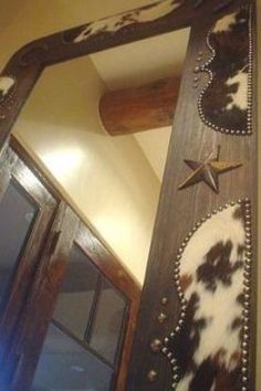 a mirror that is hanging on the wall next to a door with a cow print design