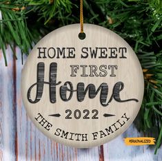 a wooden ornament hanging from a christmas tree with the words home sweet first home on it