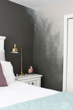 a white bed sitting in a bedroom next to a wall painted gray and white with gold accents