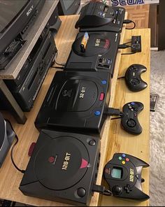 several video game consoles are lined up on a table next to each other with controllers