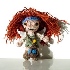 a crocheted doll with long red hair on top of a white countertop