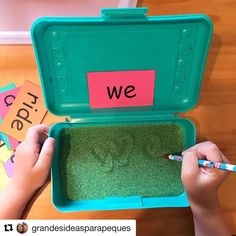 a child is writing on the inside of a green box with grass in front of it