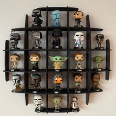 a bunch of star wars action figures are arranged in a wall mounted display case on a white wall