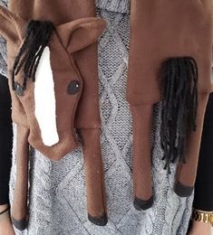 a woman wearing a brown jacket and scarf with black braids on her hair is shown from the waist up