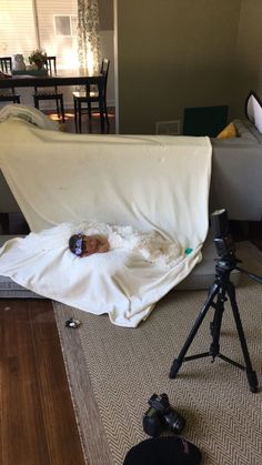 a baby is laying in a blanket on the floor next to a tripod and camera