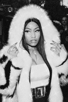 a black and white photo of a woman wearing a fur coat with her hands on her hips