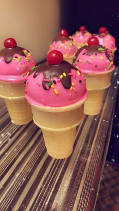 three ice cream cones with pink frosting and sprinkles