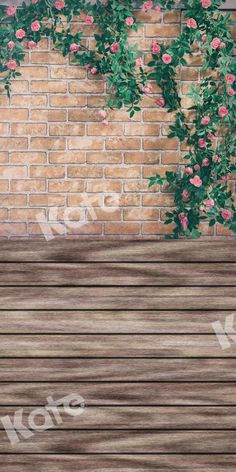 an empty wooden bench in front of a brick wall with pink flowers growing on it