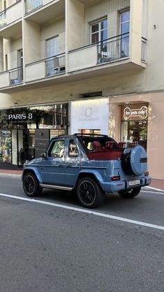 an old car is parked on the side of the road in front of a building