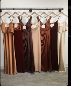 six dresses hanging on a rack in front of a wall