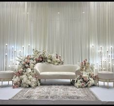 a white couch sitting on top of a rug in front of a wall covered with flowers