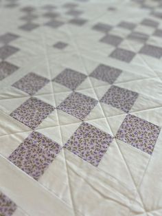 a quilted bed with purple and white squares on it