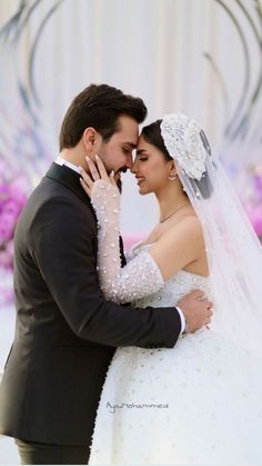 a bride and groom embracing each other in front of a floral backdrop at their wedding