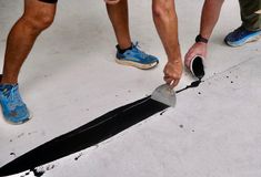 three men are painting the floor with black paint