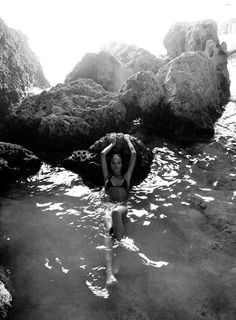 black and white photograph of a woman in the water with rocks on either side of her