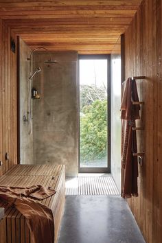 an open bathroom with wooden walls and floor to ceiling glass doors that lead out onto the outdoors