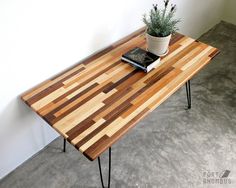 a wooden table with hairpin legs and a potted plant on top