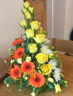 a vase filled with yellow and orange flowers on top of a wooden table