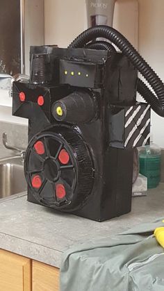 a black machine sitting on top of a kitchen counter next to a yellow object with red eyes