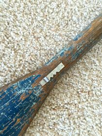 an old wooden baseball bat laying on the floor with it's blade missing from its top