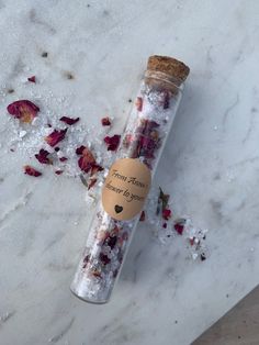 a bottle filled with flowers sitting on top of a white counter next to a piece of paper