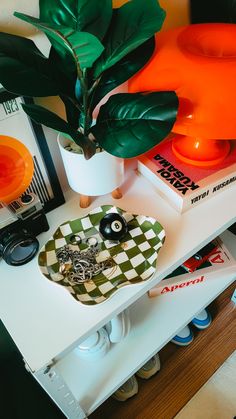 a white table topped with a green plant next to an orange lamp