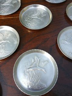 six silver plates sitting on top of a wooden table