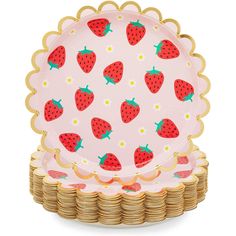 a pink plate with strawberries on it next to stacks of gold rimmed plates