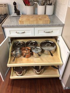 pots and pans are stored in the bottom drawer of this kitchen cabinet for storage