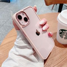 a woman holding up her pink iphone case next to a cup of coffee and a starbucks drink