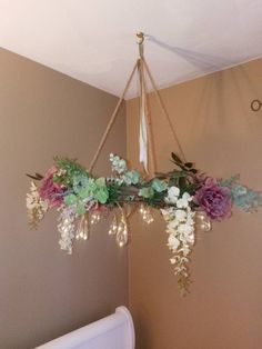 a chandelier with flowers hanging from it's sides in a bedroom next to a crib