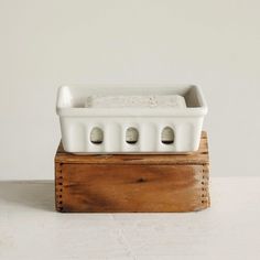 a white ceramic dish sitting on top of a wooden block with holes in it's sides