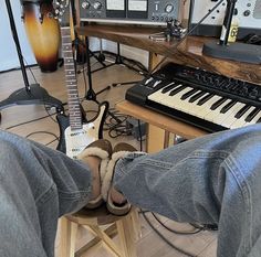 someone is sitting on a stool with their feet up in front of an electric keyboard