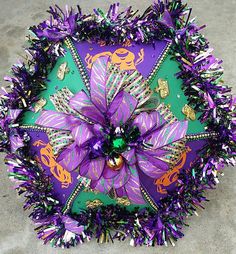 a purple and green umbrella with decorations on the top is laying on the concrete floor